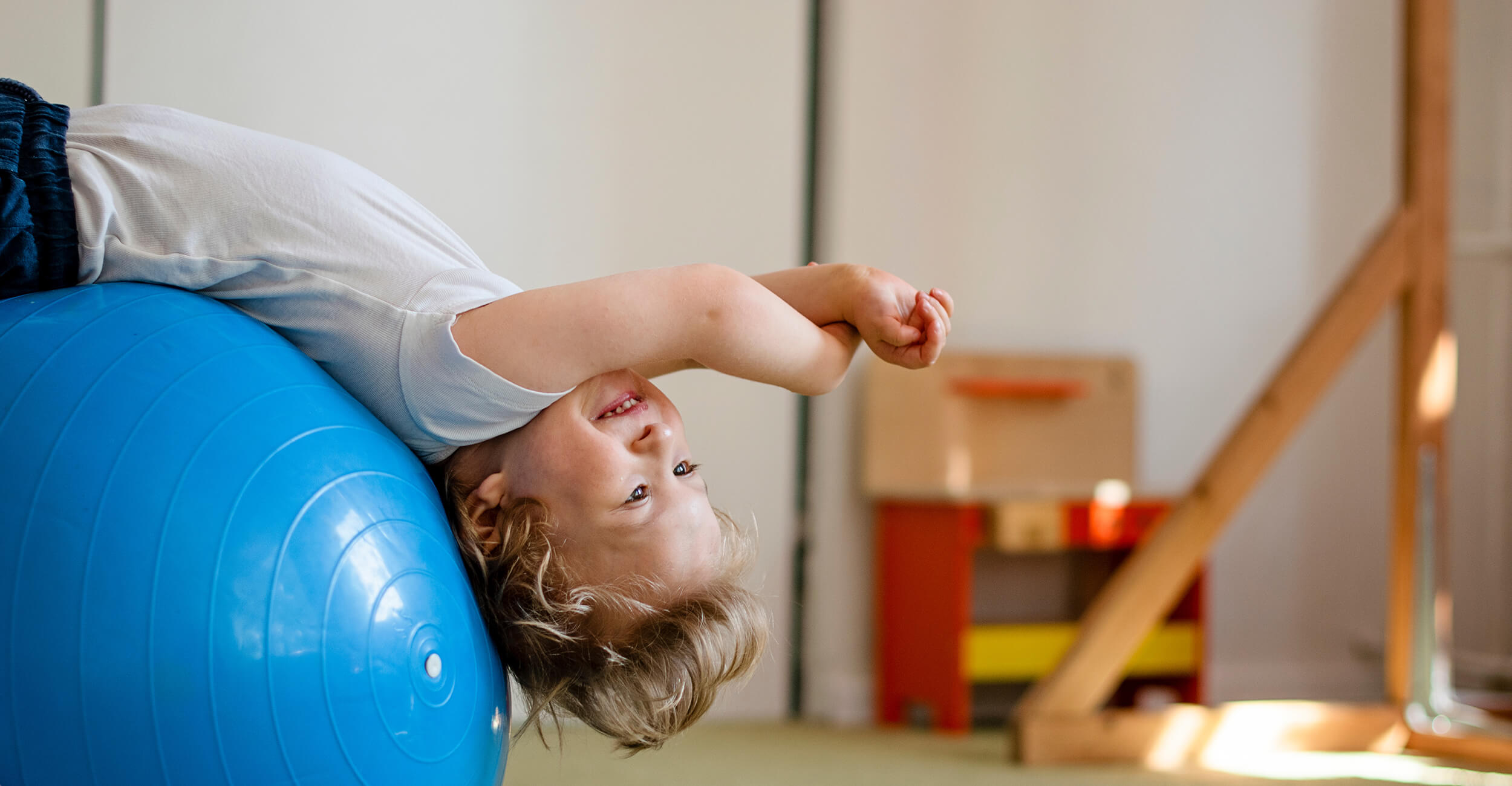 Boy with down syndrome stretching over a ball