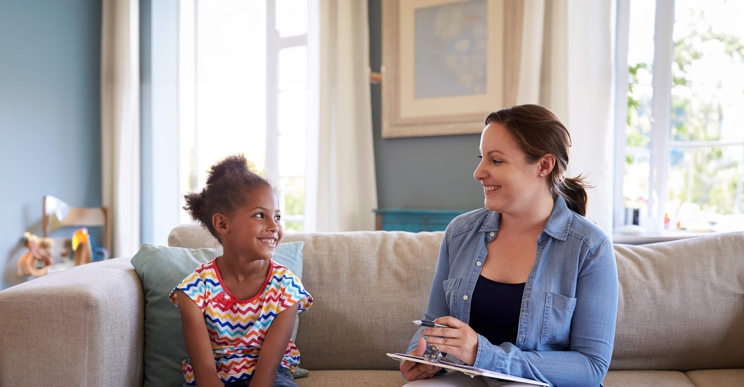 Physiotherapist sitting with a young child smiling